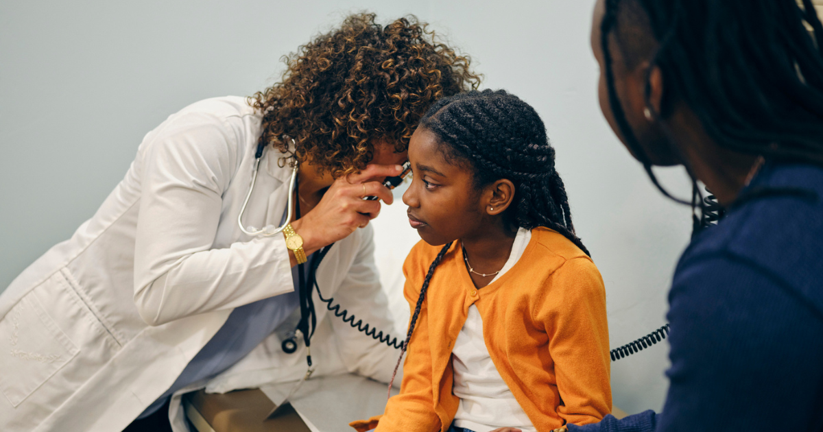 Doctor looking in girl's ear