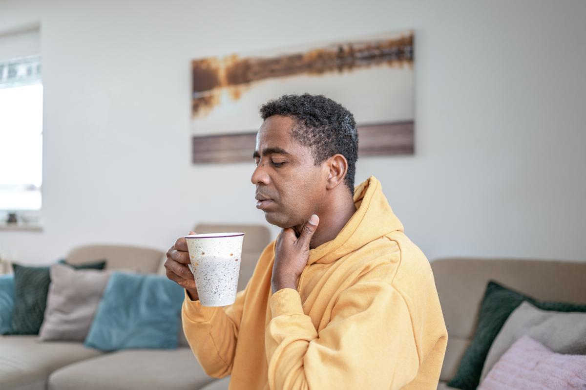 Man holding his throat drinking tea