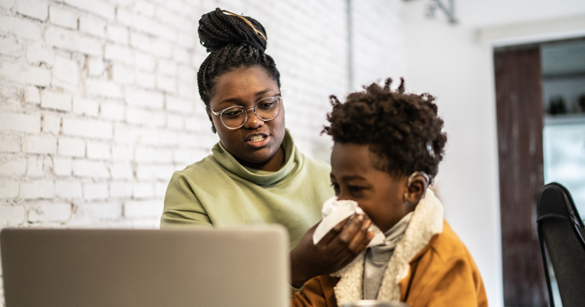 Woman helping her young son blow his nose