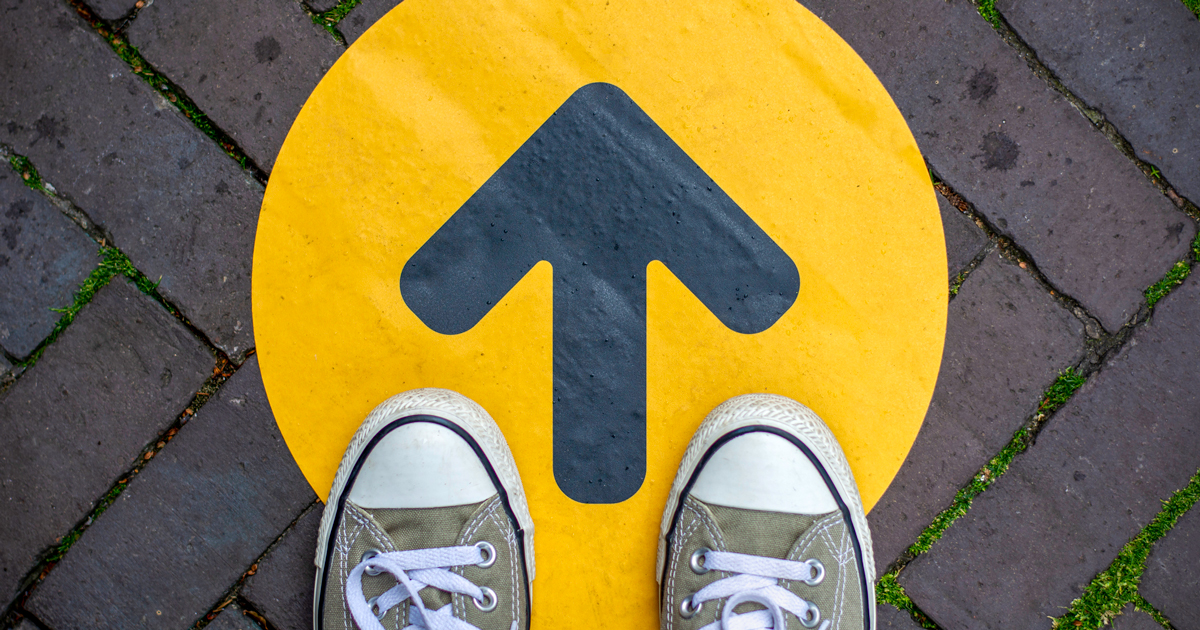 Feet standing on top of a yellow arrow