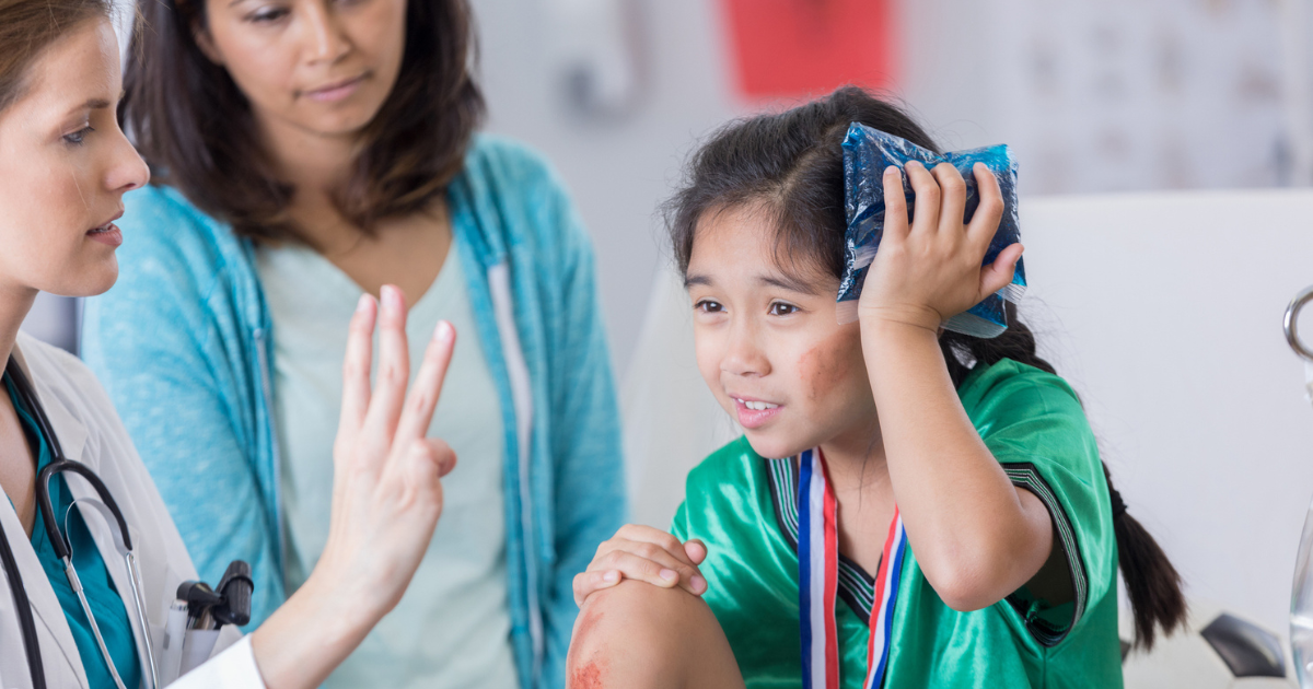 Young girl in a soccer uniform holding an ice pack against her head while a doctor holds up three fingers