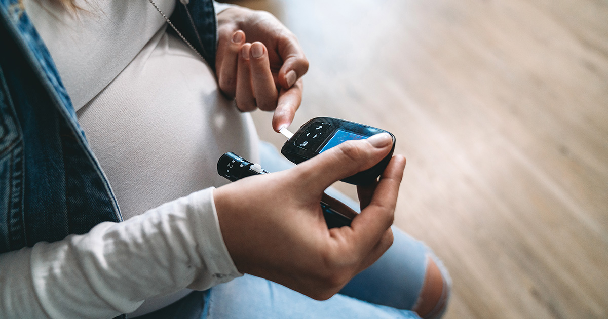 Pregnant woman using glucose meter