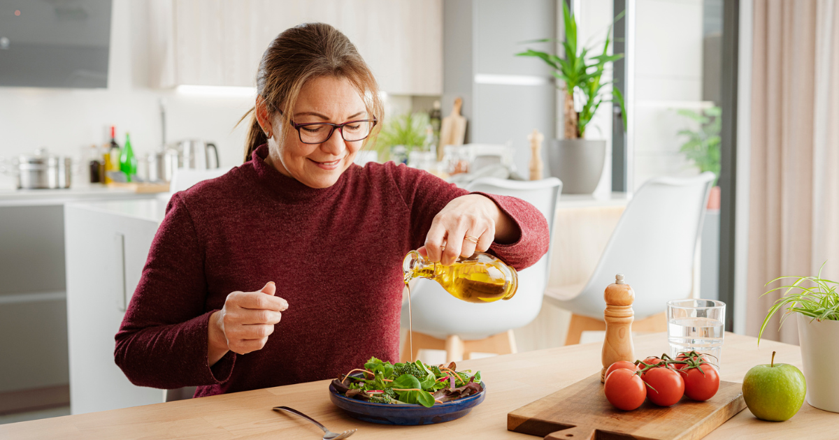 Woman pouring oil on salad