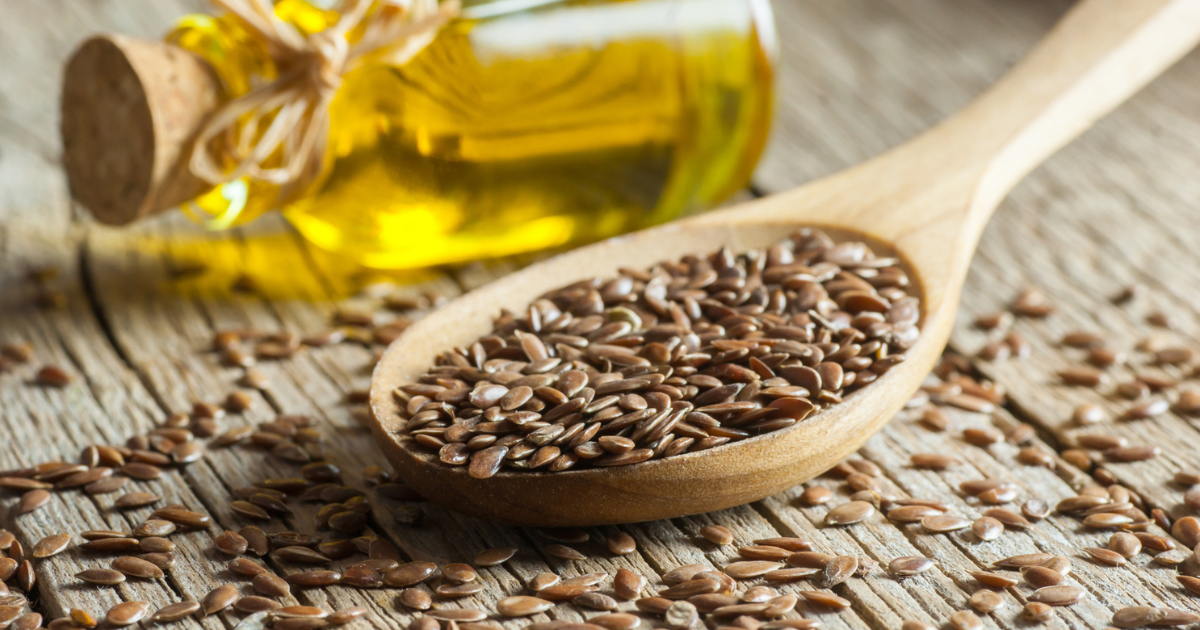 Spoonful of seeds next to a bottle of oil