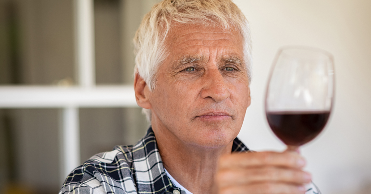 Older man holding a glass of red wine