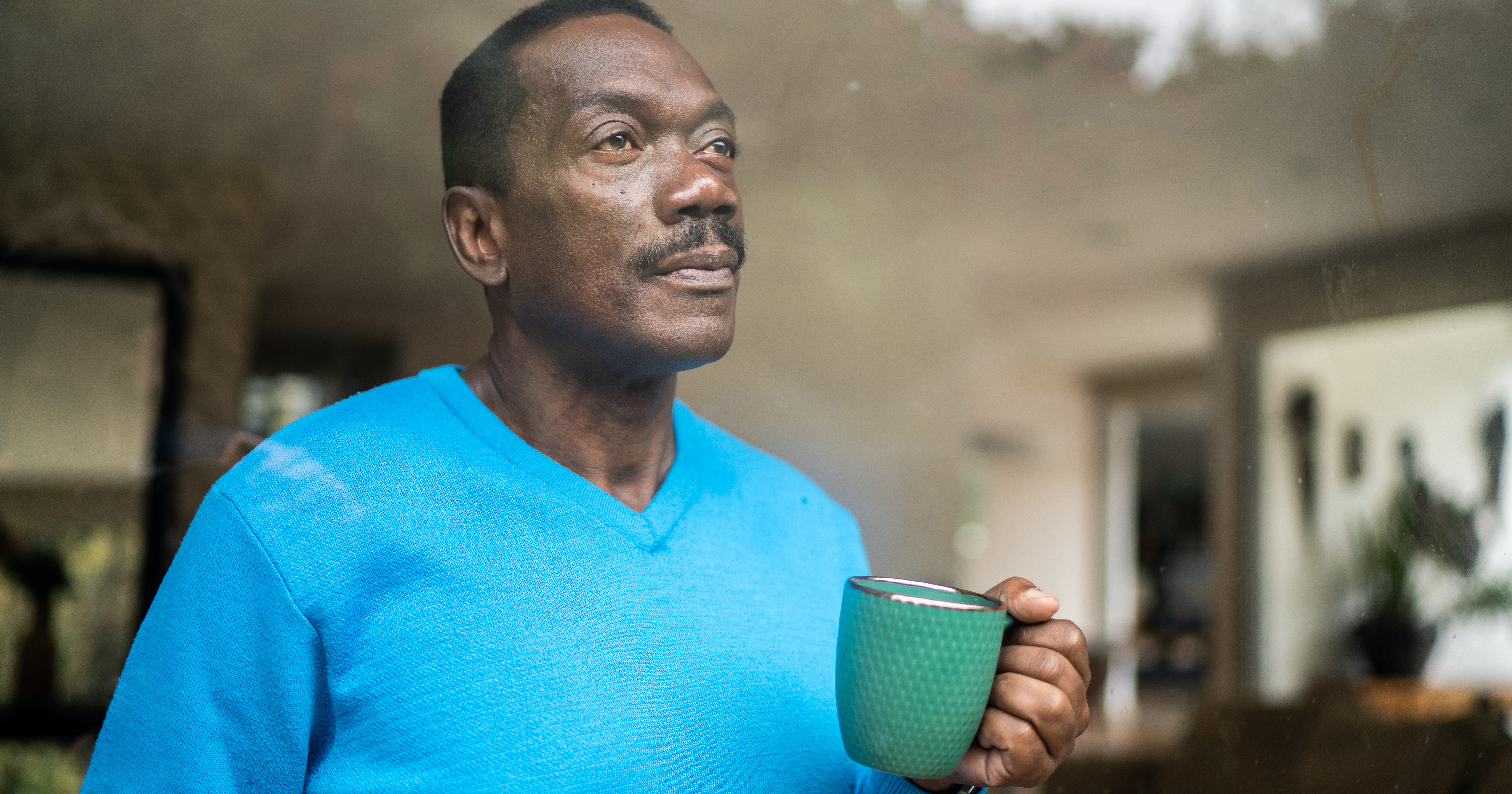 picture of a man drinking coffee looking out a window