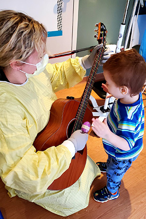 One of our music therapy experts helps a small child play guitar.
