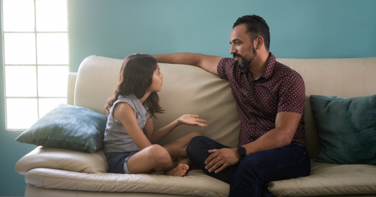 Man sitting, talking to his daughter on the couch