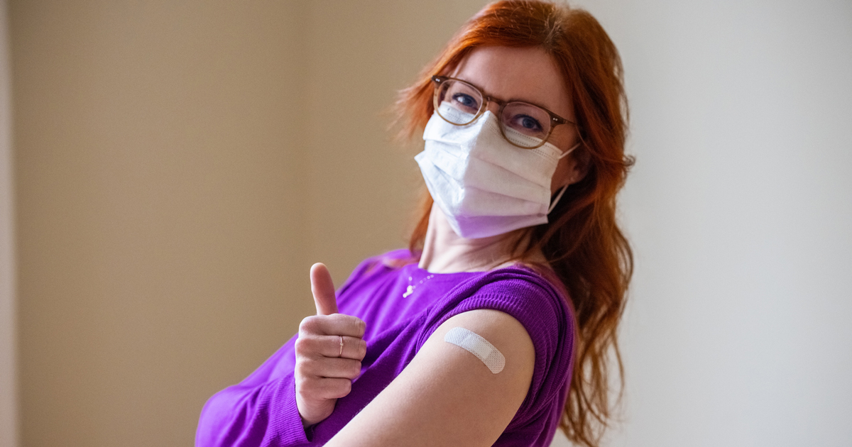 Masked woman showing off bandaid