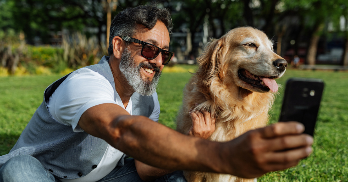 Man wearing sunglasses taking selfie with golden retriever