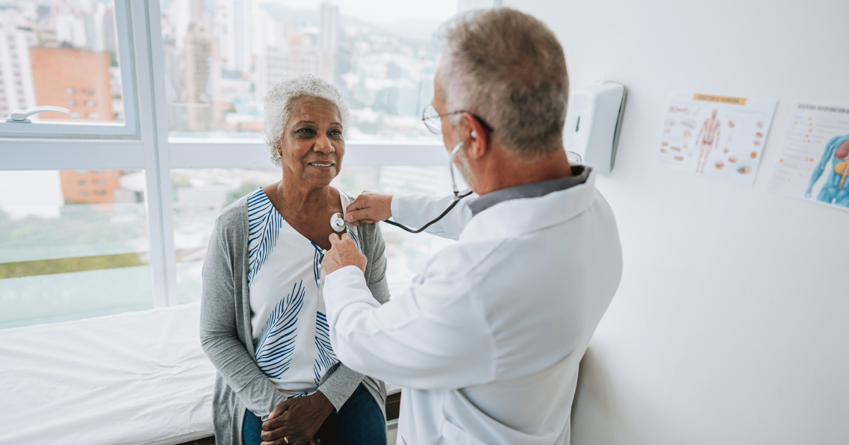 Doctor listening to older woman's heart