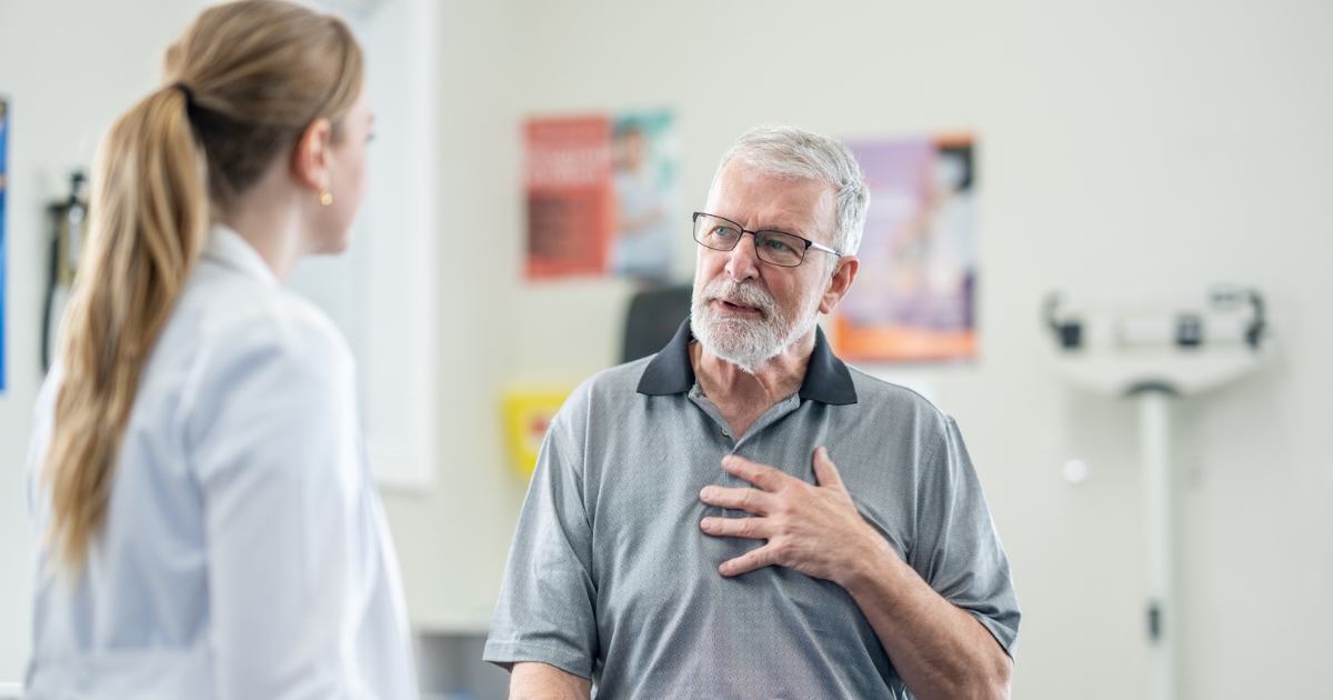 Man touching his chest and talking to doctor