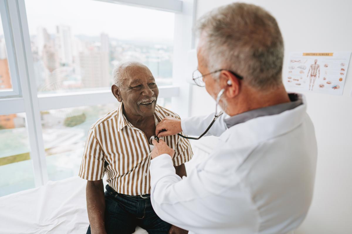 Doctor listening to man's heart