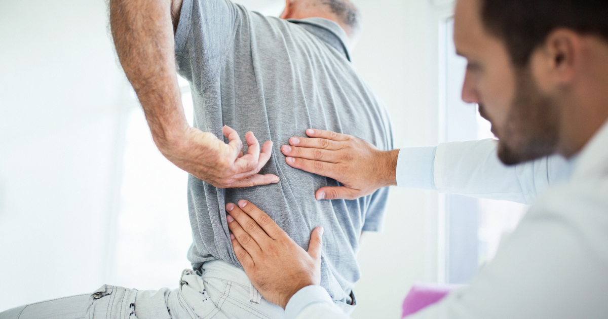 Man pointing to his back, doctor examining