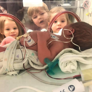Rainbow baby Theodore in the NICU, with Nora, Miles and Isla looking in.