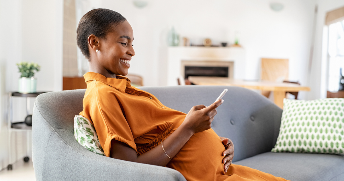 Pregnant woman sitting on the couch holding her phone