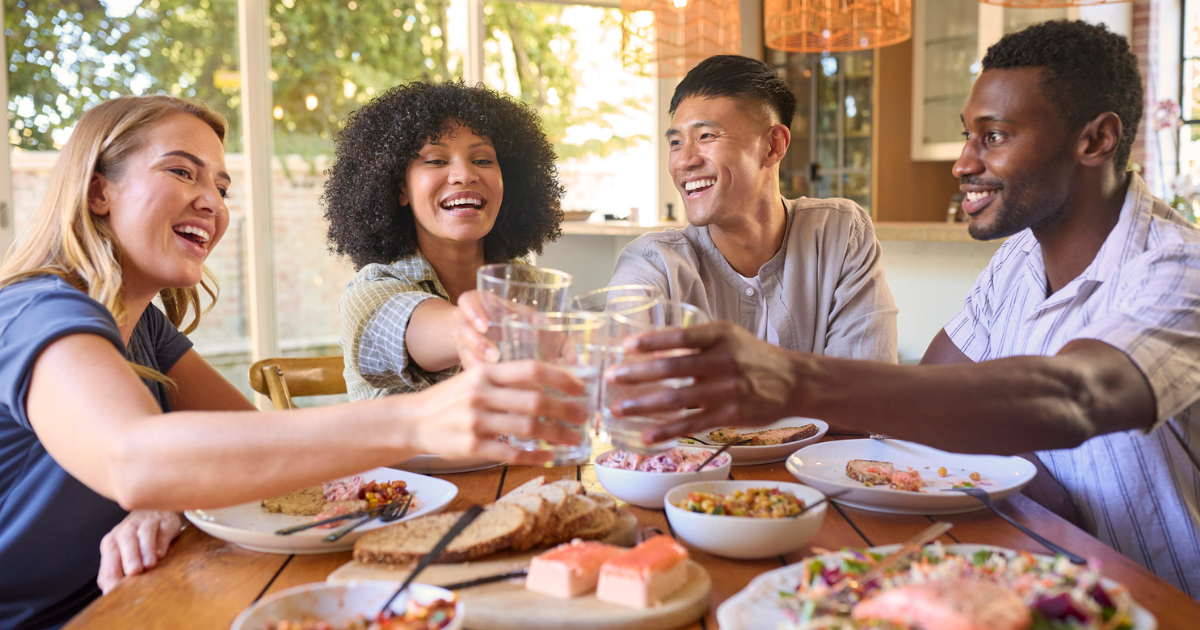 Two men and two women toasting with glasses of water