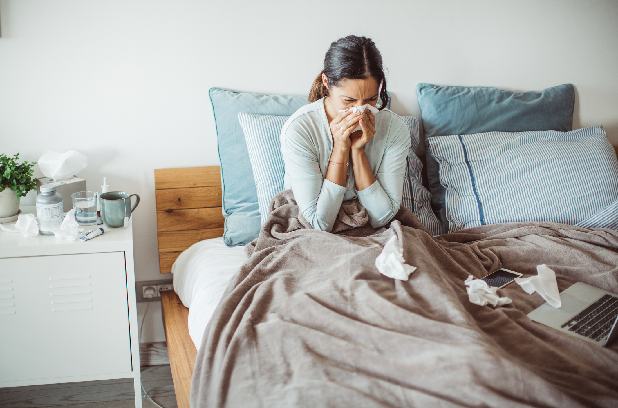 Woman blowing her nose in bed