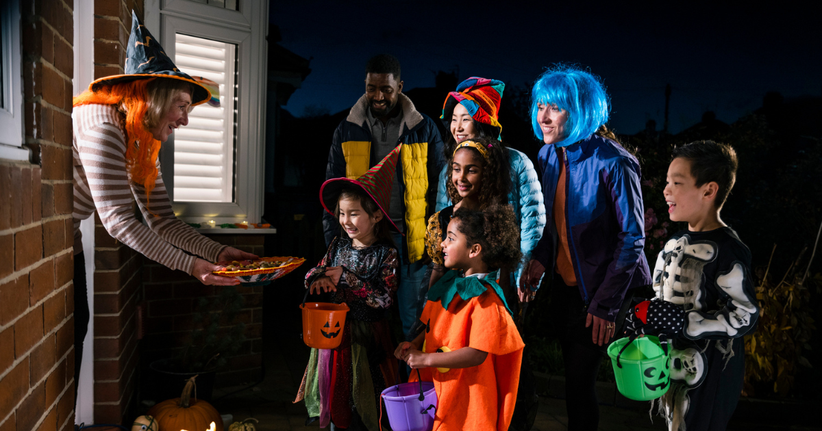 Woman handing candy to group of trick-or-treaters