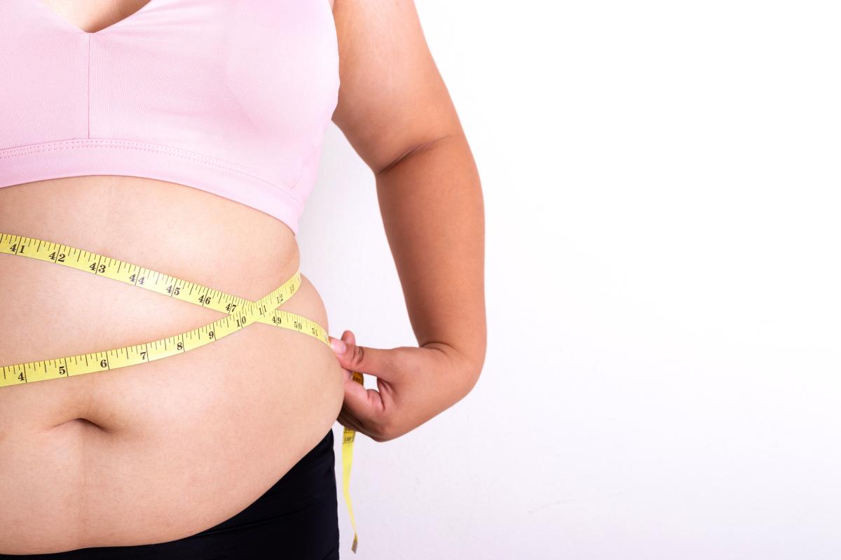 Woman holding tape measurer over stomach