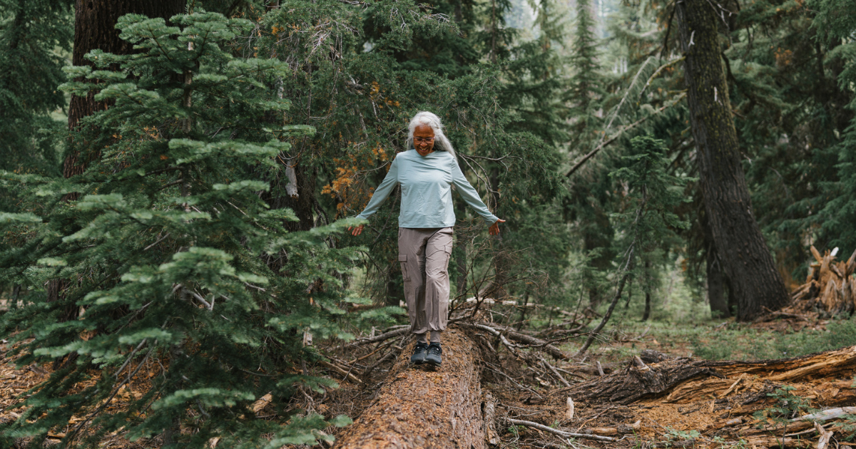 Older woman balancing on a fallen tree