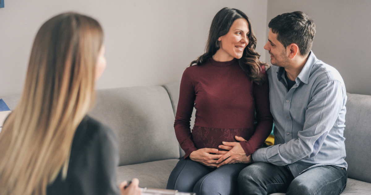 Husband and pregnant wife talking to genetic counselor