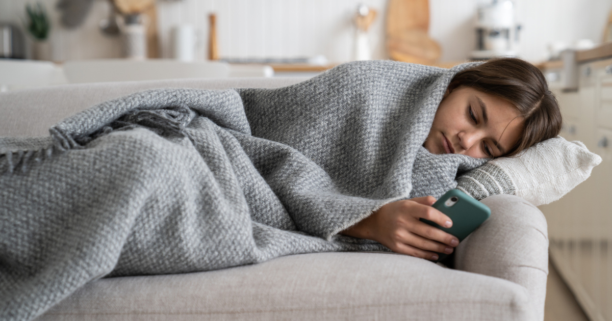 Teenage girl laying on the couch wrapped in a blanket