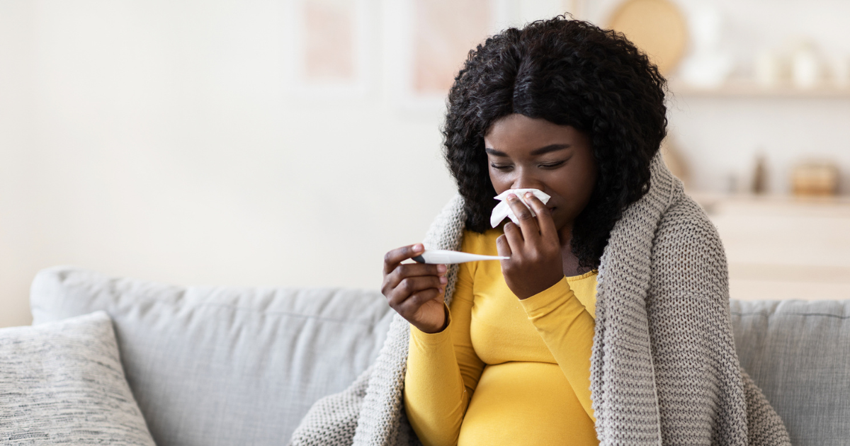 Pregnant woman holding tissue and thermometer