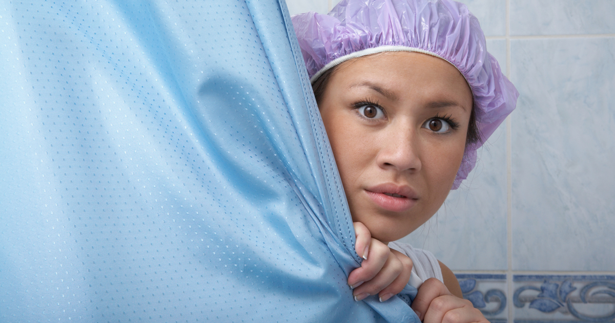 Woman peeking out from shower curtain