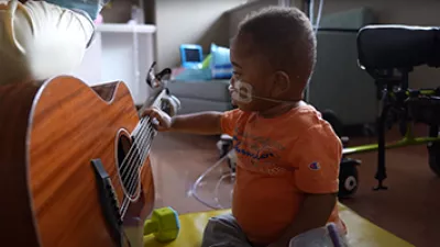 A baby is touching the strings of a guitar