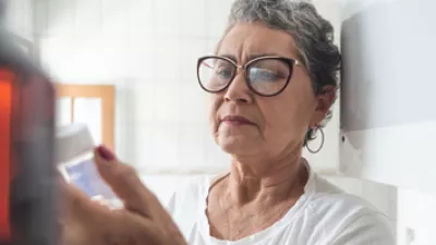 picture of a woman looking at a bottle of aspirin