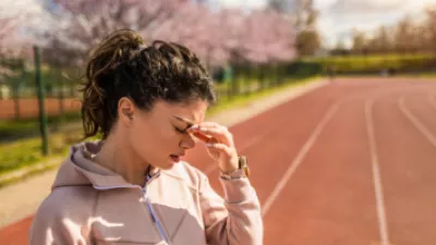 Picture of a woman on a track with a headache