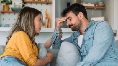 Confused man sitting on the couch with a concerned woman