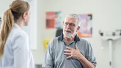 Man touching his chest and talking to a doctor