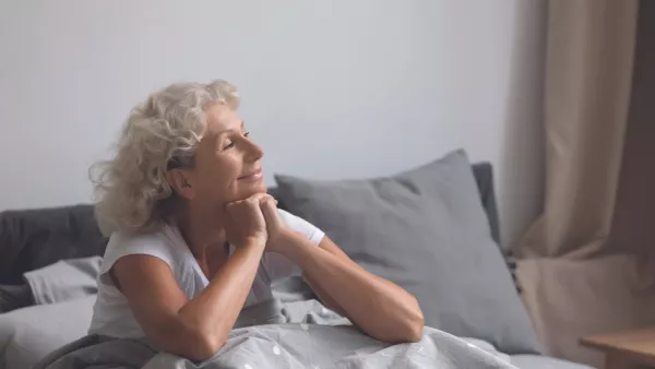 Woman sitting up smiling in bed