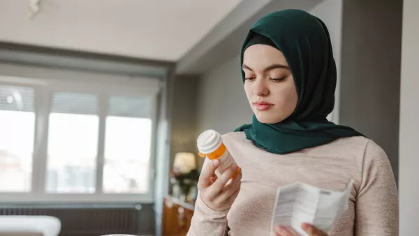 Woman wearing a hijab holding a pill bottle