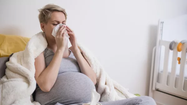 Pregnant woman blowing her nose