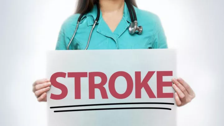 Woman holding sign that says STROKE