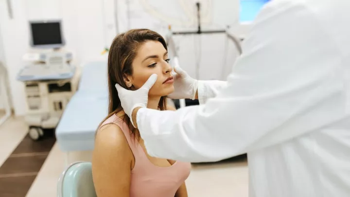 Doctor pressing on woman's sinuses