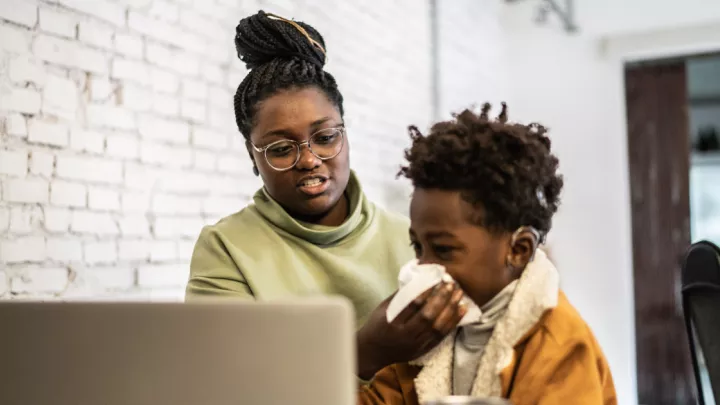 Woman helping her young son blow his nose