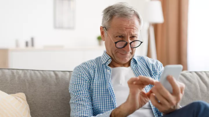 Picture of a man with glasses looking at his cellphone