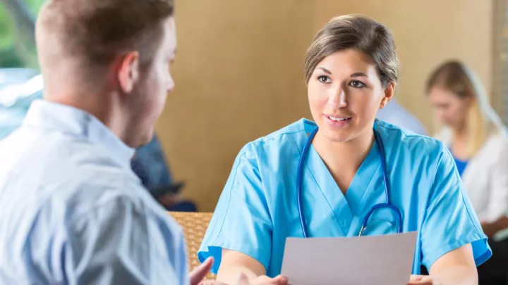 Woman in scrubs talking to man
