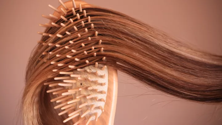 Close up of a hair brush brushing long brown hair