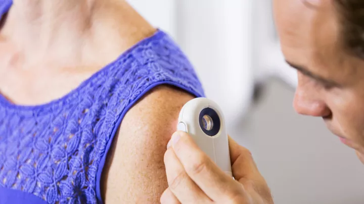 Dermatologist assessing woman's arm