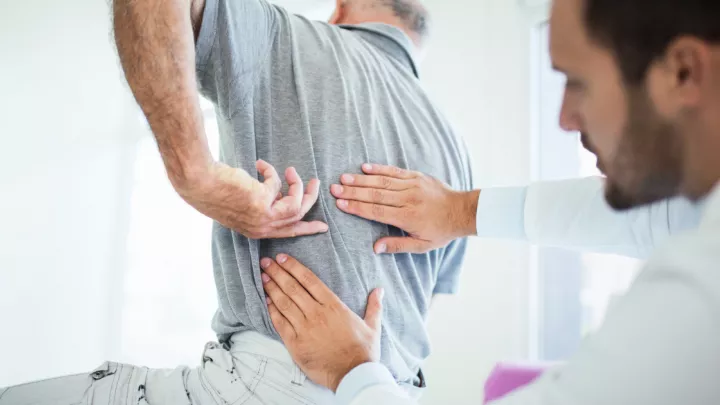 Man pointing to his back, doctor examining