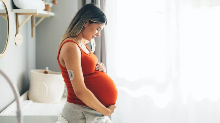 Pregnant woman wearing a glucose monitor