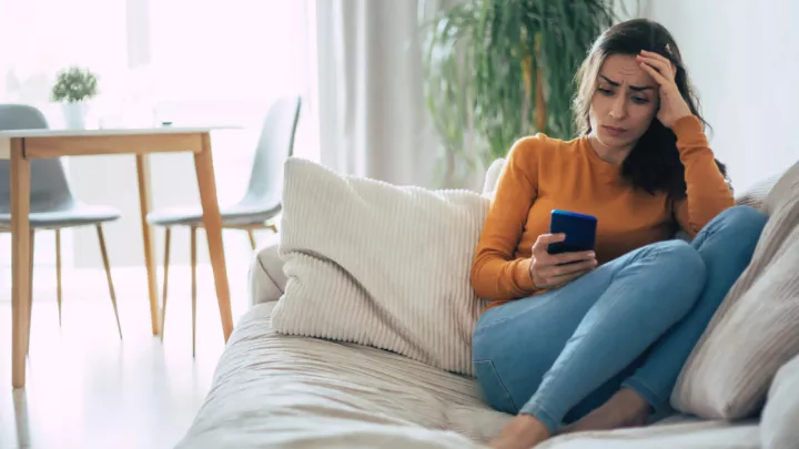 Woman sitting on couch looking at her phone