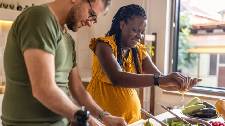 Pregnant woman and her partner making a meal