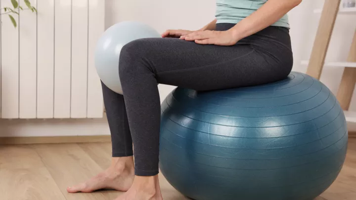 Close up of a woman's legs sitting on an exercise ball