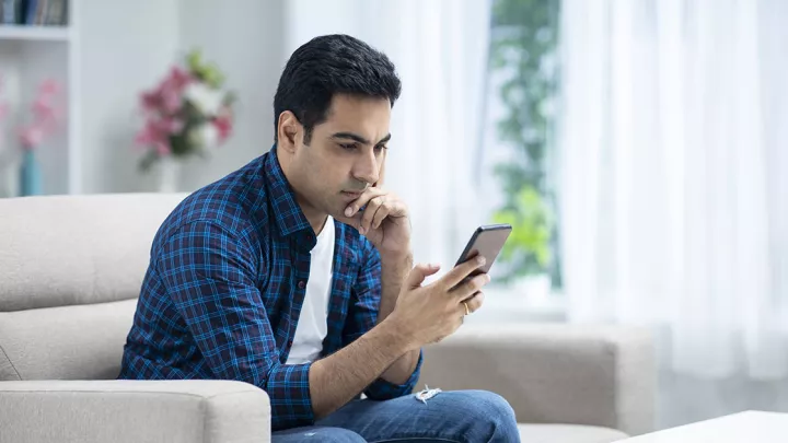 Man sitting on the couch looking at his phone
